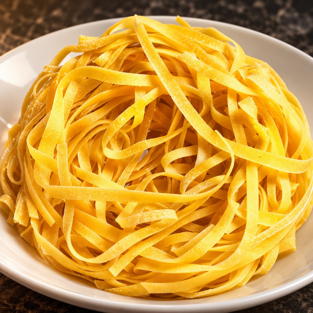 Primo piano di Fettuccine all'uovo su piatto bianco