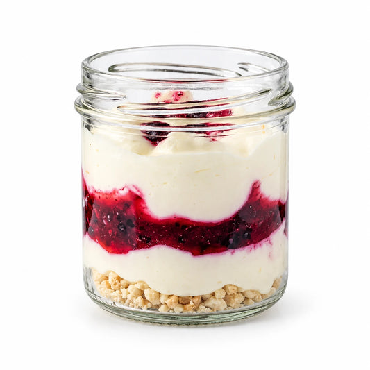 Postre de yogur con frutos rojos 80 g en vasito con capas de crema de yogur, salsa de frutos rojos y migas de galleta, sobre fondo blanco