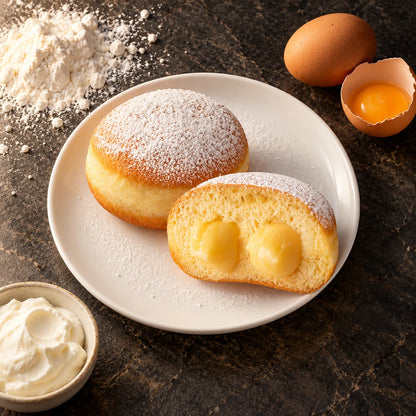 Krapfen alla Crema Vaniglia visto dall'alto su piatto bianco, con farina, un uovo e una ciotola di crema