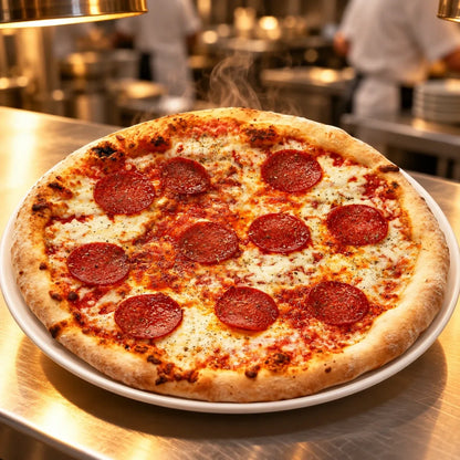 Φρεσκοψημένη Pizza με σαλάμι στον ανοξείδωτο πάγκο επαγγελματικής κουζίνας