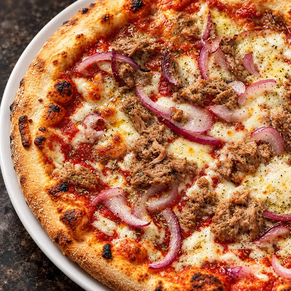 Zbliżenie: pizza z tuńczykiem i czerwoną cebulą z delikatnym tuńczykiem, krążkami czerwonej cebuli i roztopioną mozzarellą