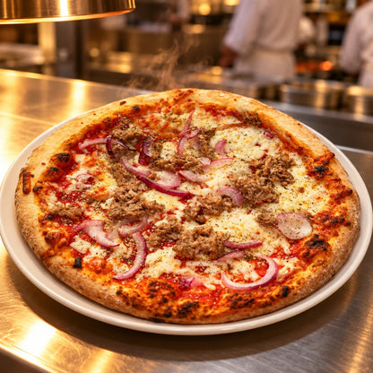 Gotowa do podania pizza z tuńczykiem i czerwoną cebulą na wydawce pod lampami grzewczymi