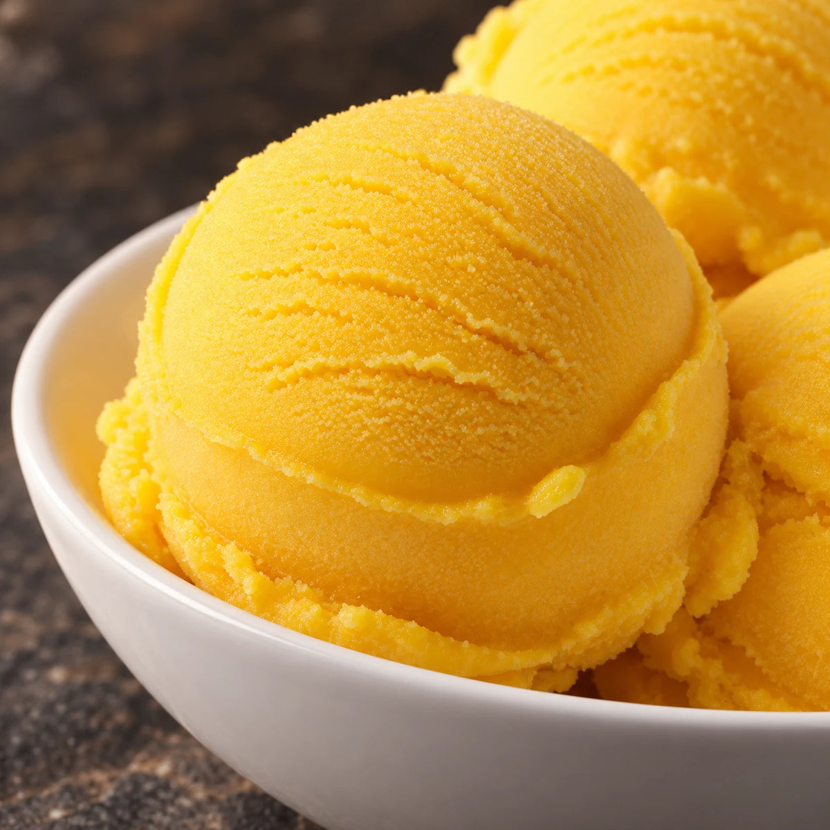 Primer plano de bolas de sorbete de mango en un cuenco blanco